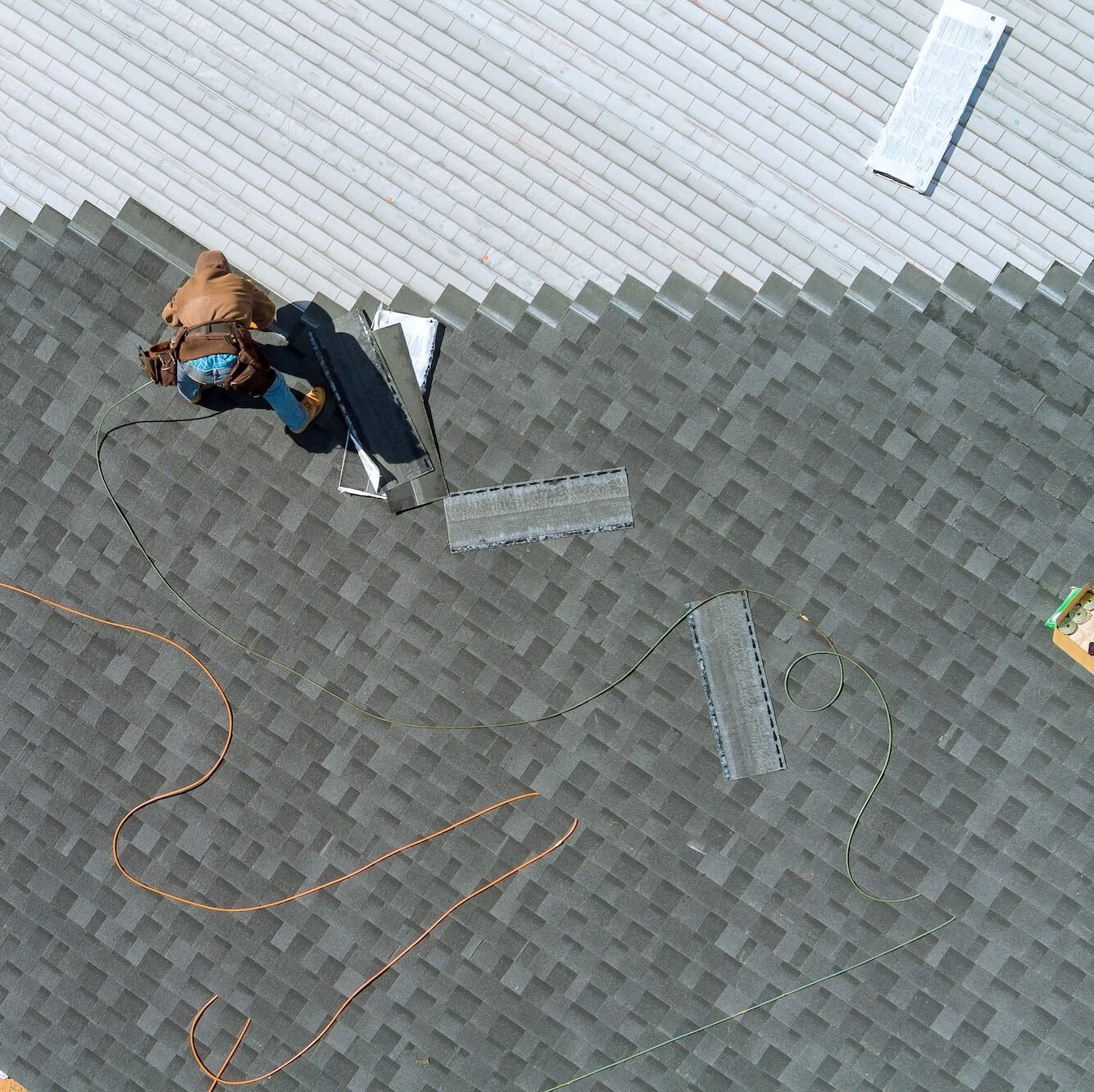 A asphalt shingles installation on the roof roofer is nailing asphalt shingles to roofing constructi